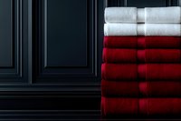 Stack of soft white and red folded towels against dark wall, luxury bathroom textile concept for home decor and hospitality design.