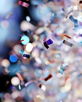 Colorful confetti and glitter floating in air with bokeh effect on blue background, creating festive atmosphere for celebration and party designs.