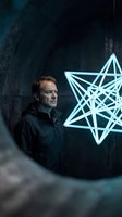 Middle-aged Caucasian man in black jacket gazing at glowing neon star symbol in dark industrial tunnel setting, representing innovation and technology concepts for business and creative projects.