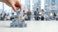 Male hand placing wooden block with lightbulb icon onto pyramid stack of business strategy symbols against blurred office cityscape background.