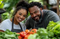 Happy African American couple cooking together in kitchen with fresh vegetables and herbs creating healthy meal at home.