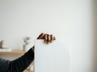 Hand holding blank white card or paper against neutral background, suitable for mockups, advertising campaigns, promotional materials, and business presentations.