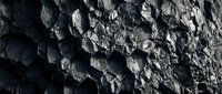 Rough textured dark stone surface with jagged rocky formations and deep shadows, suitable for backgrounds, overlays, and design projects.
