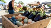 Fresh organic vegetables and fruits displayed in wooden crates at local farmers market with shoppers browsing produce stands in sunny outdoor setting.