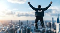 Young man in black hoodie with 2028 number jumping high above city skyline at sunset, expressing freedom and future success against urban background.