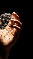 Hand holding glowing geometric wireframe sphere against black background, representing digital technology, innovation, and data connectivity for tech and business applications.