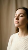 Young Caucasian woman in cream sweater meditating with eyes closed, calm serene expression, soft neutral background, mindfulness and mental wellness concept.