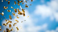 Golden confetti pieces falling through bright blue sky with white clouds creating festive celebration atmosphere for party events and special occasions.