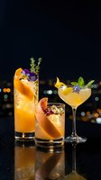 Three elegant orange cocktails garnished with herbs and edible flowers on dark background with city lights bokeh for bar menu and beverage photography.