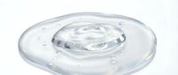 Clear liquid droplet forming concentric ripples on transparent gel surface, isolated on white background for design and product mockup use.