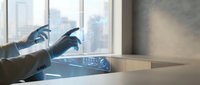 Businessman using futuristic holographic interface technology at modern office desk with city view through windows for digital innovation concepts.