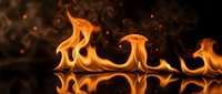 Intense orange flames dancing with glowing sparks against dark background creating dramatic fire effect for energy and power concepts.
