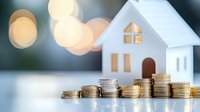 Small white model house with stacks of coins in ascending order against blurred bokeh background, representing property investment and mortgage savings growth.