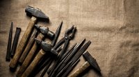 Vintage woodworking tools collection with hammers, chisels and hand tools arranged on rustic burlap background for craftsmanship projects.