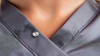 Elegant gray silk blouse with crystal button detail shown in close-up view, highlighting luxurious fabric texture and sophisticated neckline design for fashion and style concepts.