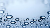 Water droplets on blue surface creating natural abstract background with copy space for text and design applications.