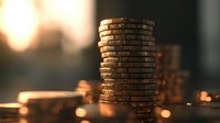 Stack of golden coins in warm sunset lighting with blurred background, creating atmospheric financial composition for business and investment concepts.