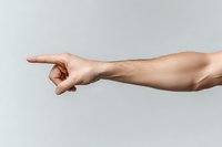 Caucasian female arm and hand pointing finger to side against light gray background, showing direction, guidance or choice concept for business presentations.