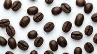 Roasted coffee beans scattered on white background, perfect for cafe branding, beverage packaging, culinary designs and coffee shop marketing materials.