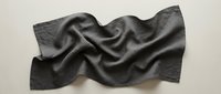 Dark gray fabric with flowing waves and soft folds creating elegant textile texture for fashion design and interior decoration projects.