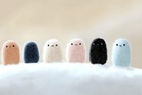 Cute fluffy ghost characters in pastel colors lined up on white surface. Kawaii style plush toy monsters with simple faces showing different expressions and textures.
