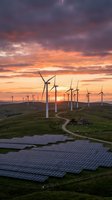 Wind turbines and solar panels on green hills at dramatic sunset showcasing renewable energy infrastructure and sustainable power generation technology.