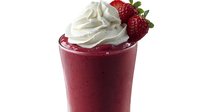 Fresh strawberry smoothie topped with swirled whipped cream and garnished with ripe strawberries against dark background, creamy texture for beverage menu photography.