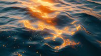 Mesmerizing ocean waves at golden sunset with sunlight reflecting on rippling water surface creating glowing patterns and sparkles in deep blue sea.