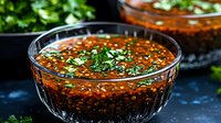 Spicy red chili sauce with herbs in glass bowl, perfect condiment for Asian cuisine, cooking and food preparation backgrounds.