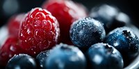 Fresh raspberries and blueberries with morning dew drops in macro photography on dark background, selective focus creates dreamy bokeh effect for food styling.