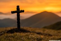 Wooden cross silhouette on grassy hilltop against dramatic orange sunset sky and mountain landscape, creating spiritual atmosphere for religious concepts.