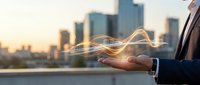 Businessman holding glowing light wave energy in palm against city skyline at sunset, representing innovation, technology, and business growth for corporate concepts.