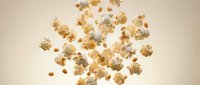 Flying popcorn kernels scattered in air against neutral beige background, perfect for snack food advertising and cinema marketing materials.