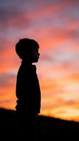 Child silhouette against dramatic sunset sky with vibrant orange pink purple clouds creating peaceful contemplative mood for inspiration concepts.
