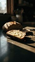 Freshly sliced artisan bread with butter on wooden cutting board in warm natural sunlight, showcasing rustic bakery products for food and culinary design projects.