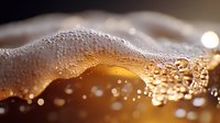 Golden liquid with bubbles and foam in macro shot, refreshing beverage with carbonation and fizzy texture against dark background, suitable for beverage advertising.