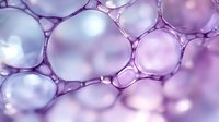 Macro view of purple and pink soap bubbles creating abstract organic pattern with soft bokeh effect and translucent cellular structure. Scientific background.