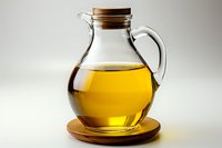 Glass pitcher with golden olive oil on wooden coaster against neutral background, cork stopper and handle, clear container showing liquid transparency.