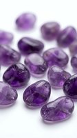 Collection of polished amethyst gemstones scattered on white background for jewelry making, crystal healing and spiritual wellness practices.