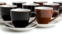Elegant coffee cups and saucers in black and brown colors arranged in rows on white background, showcasing modern minimalist design for cafe and restaurant settings.