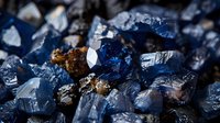 Macro shot of raw blue sapphire crystals and minerals showing natural formation texture and rough surfaces in dark environment, luxury gemstone background.
