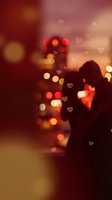Romantic couple silhouette with heart bokeh overlay and warm city lights creating dreamy Valentine's Day atmosphere for love themed designs.