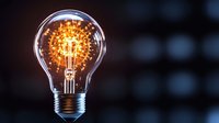 Glowing vintage Edison light bulb with warm filament against dark blurred background. Creative innovation and bright idea concept for business presentations.