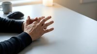 Business professional hands gesturing during meeting or presentation at modern office desk with coffee cup and computer mouse in background.
