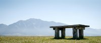 Ancient stone structure standing alone in vast grassland with distant mountains under clear sky, suitable for travel, history, and landscape design projects.