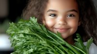 Mixed race girl with curly hair smiling while holding fresh green parsley, promoting healthy eating habits and organic food lifestyle for children.