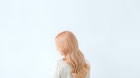 Woman with long wavy blonde hair wearing light beige sweater, rear view against white background, suitable for hair care, beauty, and fashion design projects.