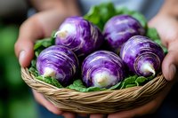 Fresh purple kohlrabi bulbs with green leaves in wicker basket held by hands. Natural organic vegetables from local farm garden harvest.
