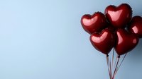 Red heart-shaped balloons floating against light blue background, romantic celebration concept for Valentine's Day, weddings, anniversaries and love declarations.