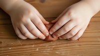 Hands positioned on wooden surface showing natural skin texture and fingernails in relaxed gesture for health and beauty concepts.